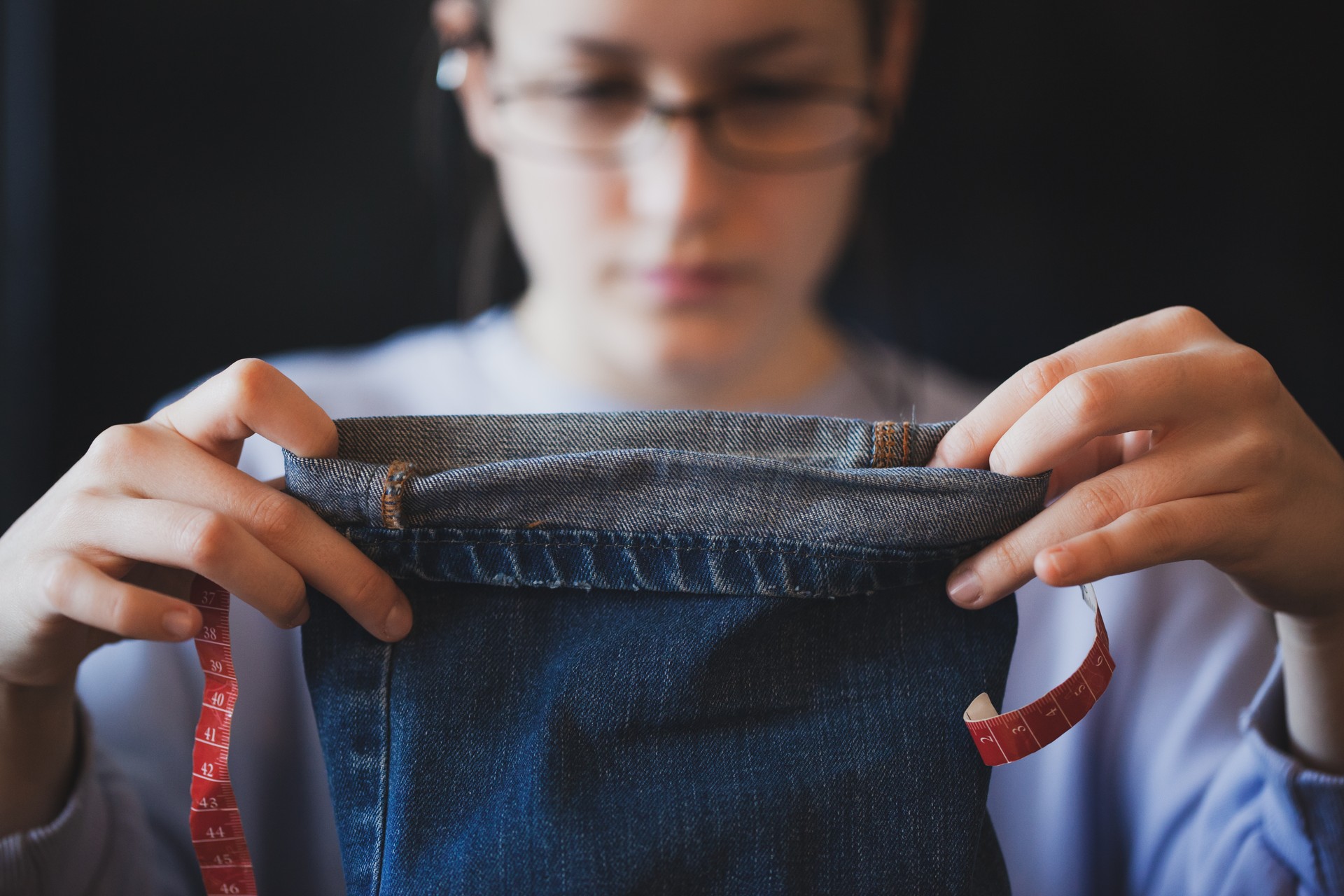 Young dressmaker woman sews clothes on sewing machine